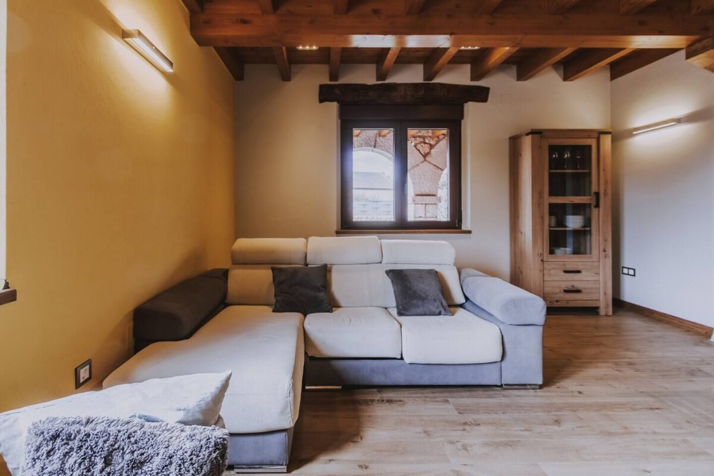 Una habitación acogedora con un sofá modular, un mueble bajo y una ventana con vistas.