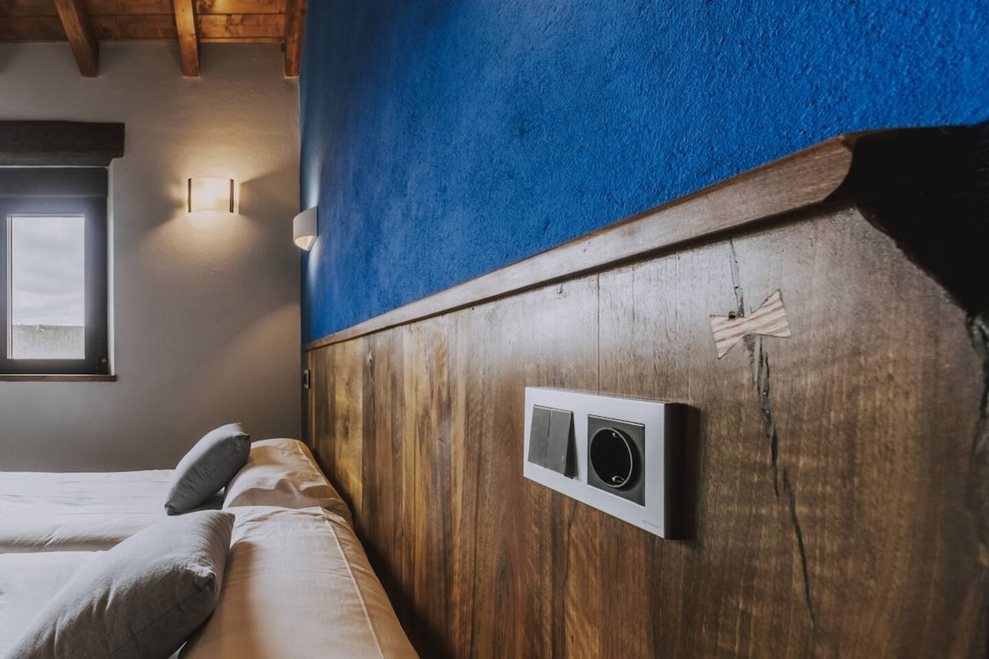 Un dormitorio con cabecera de madera, una ventana y un aire acondicionado instalado en la pared.
