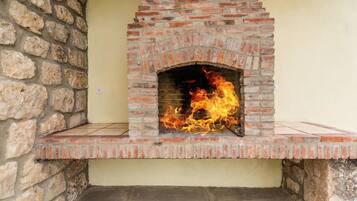 A brick-built outdoor fireplace with a fire burning inside.