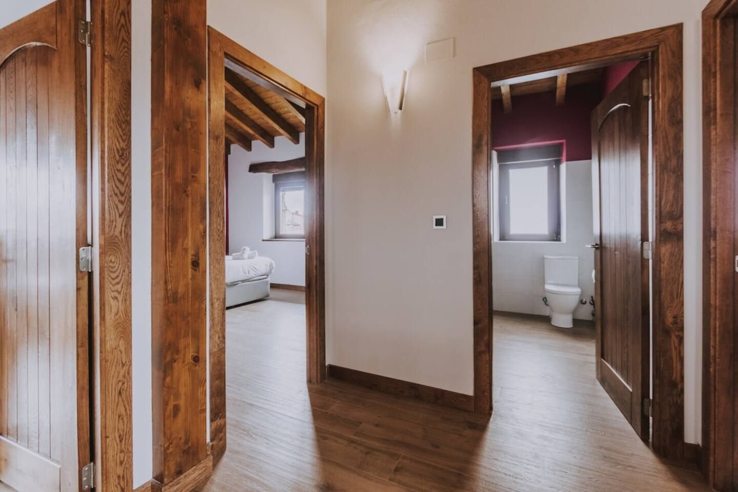 Un pasillo con puertas de madera que dan a un dormitorio y un baño.