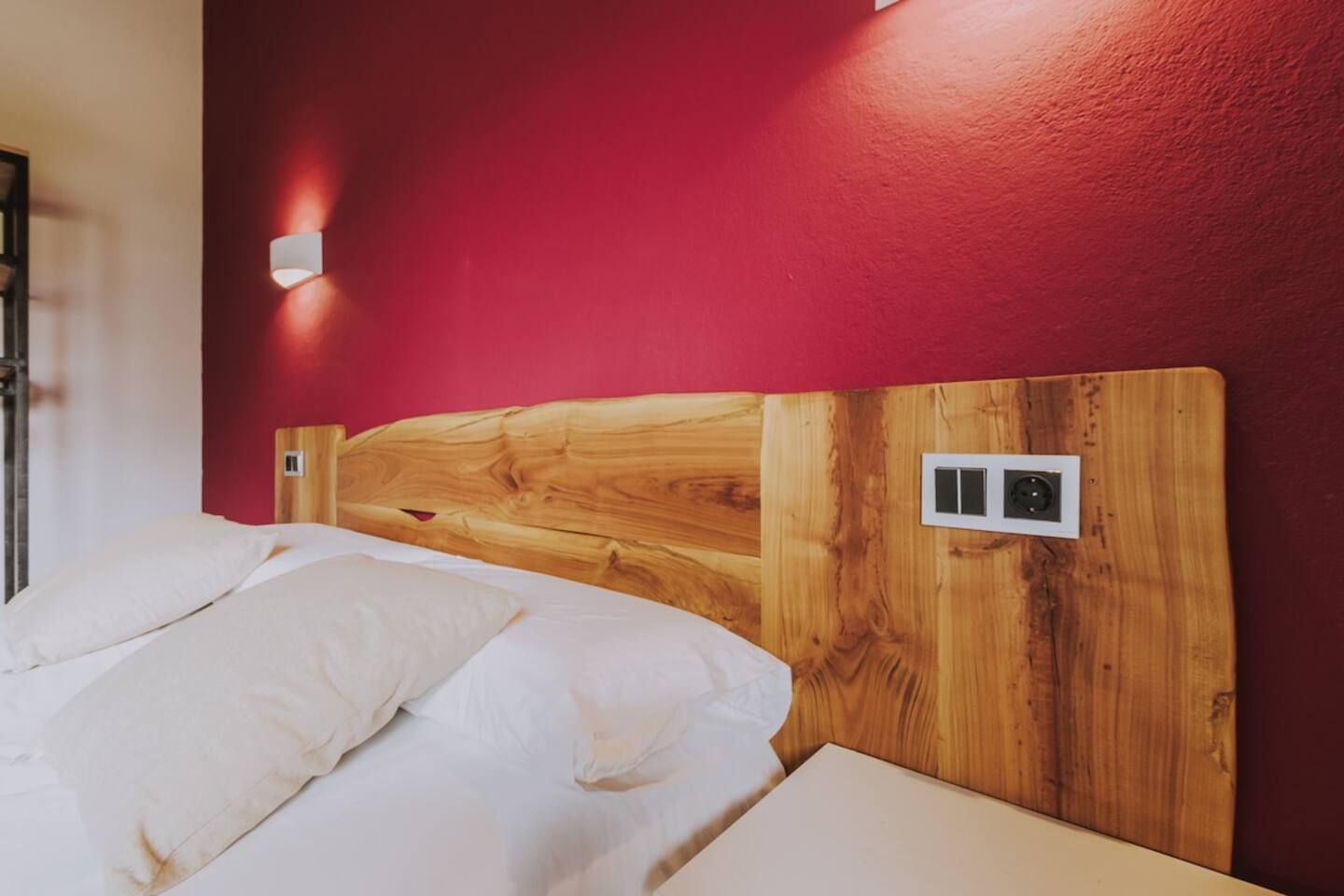 Una cama con cabecera de madera y pared roja.