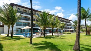 Un complexe hôtelier doté d’une piscine, de palmiers et d’un immeuble à plusieurs étages avec des balcons.