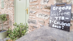 A stone building with a green door and a welcome sign. - Tyn Y Ceubren Bach at Evelyns Retreat (Corwen)