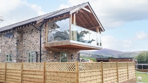 A stone building with a wooden balcony and a fenced yard. - Tyn Y Ceubren Bach at Evelyns Retreat (Corwen)
