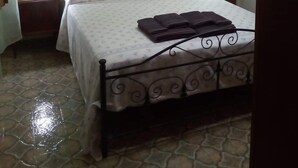 A bedroom with a bed, a nightstand, a wall-mounted picture, and a ceiling light fixture. - Villa Maristella 1 a stone's throw from the sea (Capilungo)