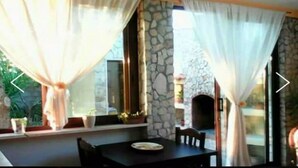 A dining area with a stone wall, a fireplace, and a table with a plate. - Villa Maristella 1 a stone's throw from the sea (Capilungo)