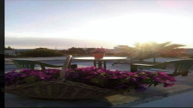 A patio area with a round table and chairs, surrounded by purple flowers and a wicker basket. - Villa Maristella 1 a stone's throw from the sea (Capilungo)