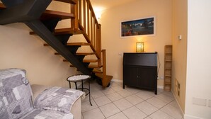 Un escalier avec des rampes en bois, un canapé, une petite table, un meuble et un tableau encadré au mur.