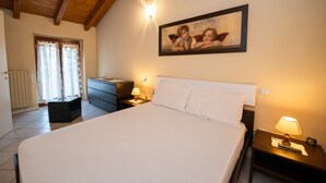 Une chambre à coucher avec un grand lit, une table de chevet avec une lampe, une commode et un tableau au mur.