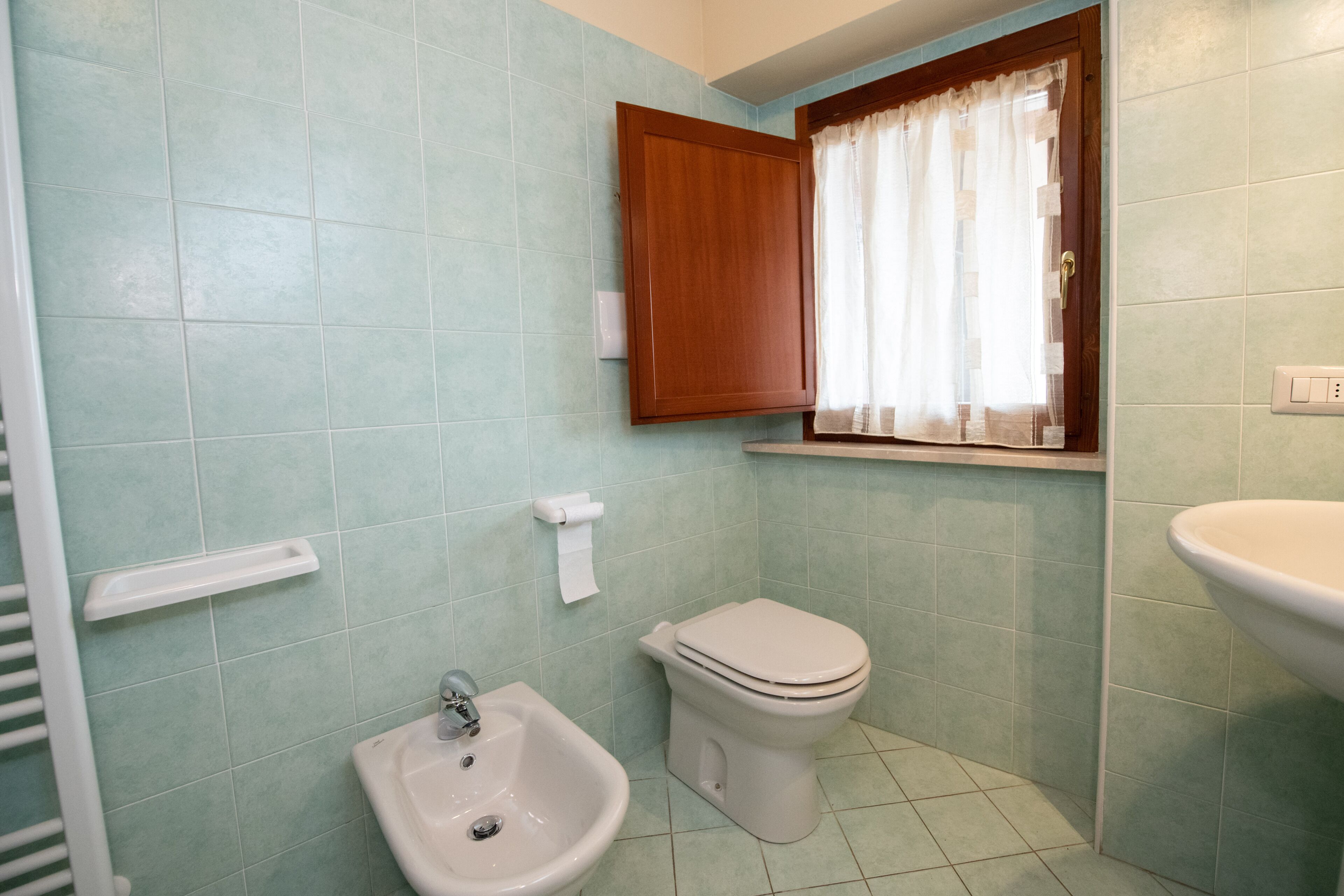 A bathroom with a sink, toilet, and cabinet.