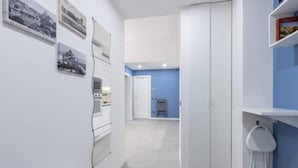 En modern inredning med ett köksområde, en hall som leder till ett rum med en blå accentvägg och en vit garderob.