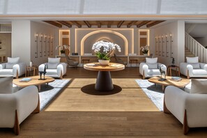 A hotel lobby with a central round table, seating arrangements, and a reception desk. - Maysan Doha Lxr Hotels & Resorts (Al Rayyan)