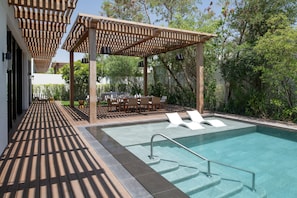 A pool area with a wooden deck, lounge chairs, and a pergola structure. - Maysan Doha Lxr Hotels & Resorts (Al Rayyan)