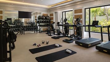 Un gimnasio con cintas de correr, elípticas, pesas libres y pelotas de ejercicio.