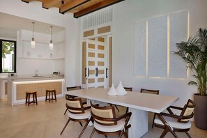 A modern kitchen with a central island, wooden chairs, and pendant lighting. - Maysan Doha Lxr Hotels & Resorts (Al Rayyan)