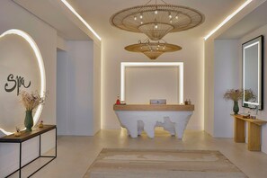 A modern reception area with a unique white console, a large mirror, and a decorative ceiling light. - Maysan Doha Lxr Hotels & Resorts (Al Rayyan)