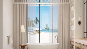 Un bagno moderno con una vasca freestanding, un'ampia finestra vista spiaggia e un mobile lavabo minimalista con ripiani.