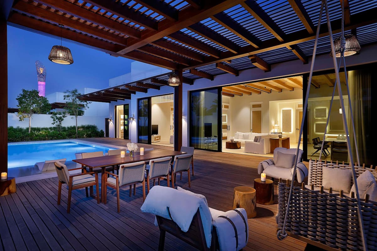 A modern outdoor deck with a pool, wooden furniture, and a hanging chair.