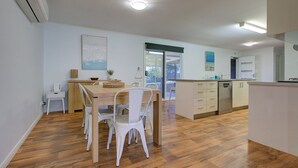 Une cuisine moderne avec une table à manger en bois, des chaises blanches et un lave-vaisselle encastré.