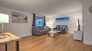 A modern living room with two grey sofas, a wooden coffee table, and a TV on a stand.