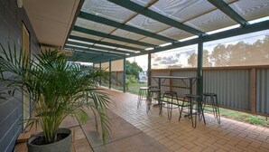 A covered patio area with a seating arrangement and a potted plant.