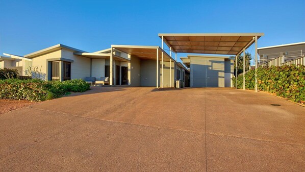A modern residential building with a covered driveway, a garage, and a landscaped garden area. - Amberjack is an outdoor lovers delight. (Exmouth)
