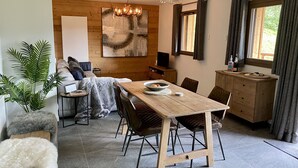 Una sala de estar moderna con una mesa de comedor de madera, asientos cómodos, un cuadro abstracto grande y un televisor.