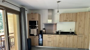 Una cocina moderna con armarios de madera, horno empotrado y campana extractora de acero inoxidable.