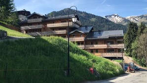 Un edificio de madera de varios pisos con balcones, frente a un paisaje de montañas y cielos despejados.