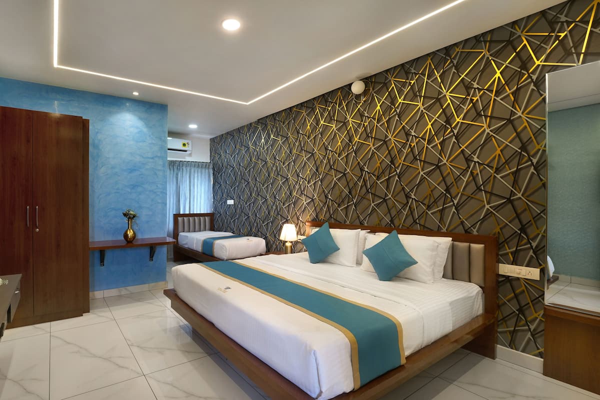 A modern hotel room with a large bed, a TV, a wooden wardrobe, and a decorative wall.