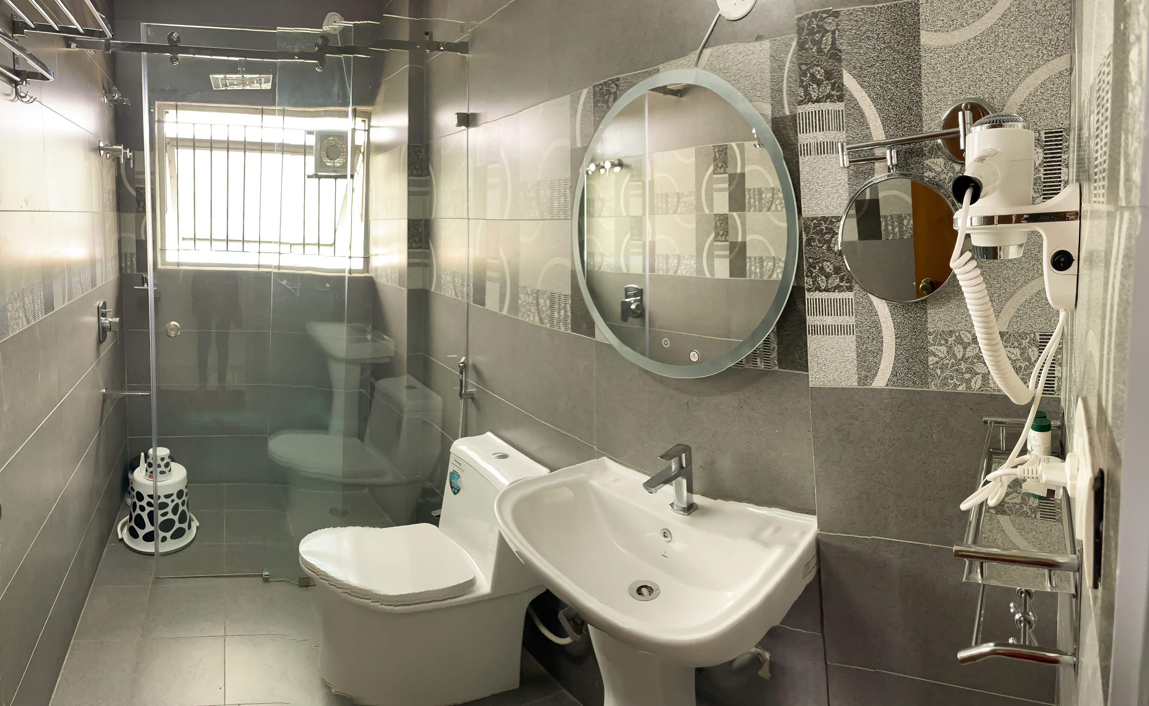 A modern bathroom with a glass-enclosed shower, a toilet, a sink, and a mirror.