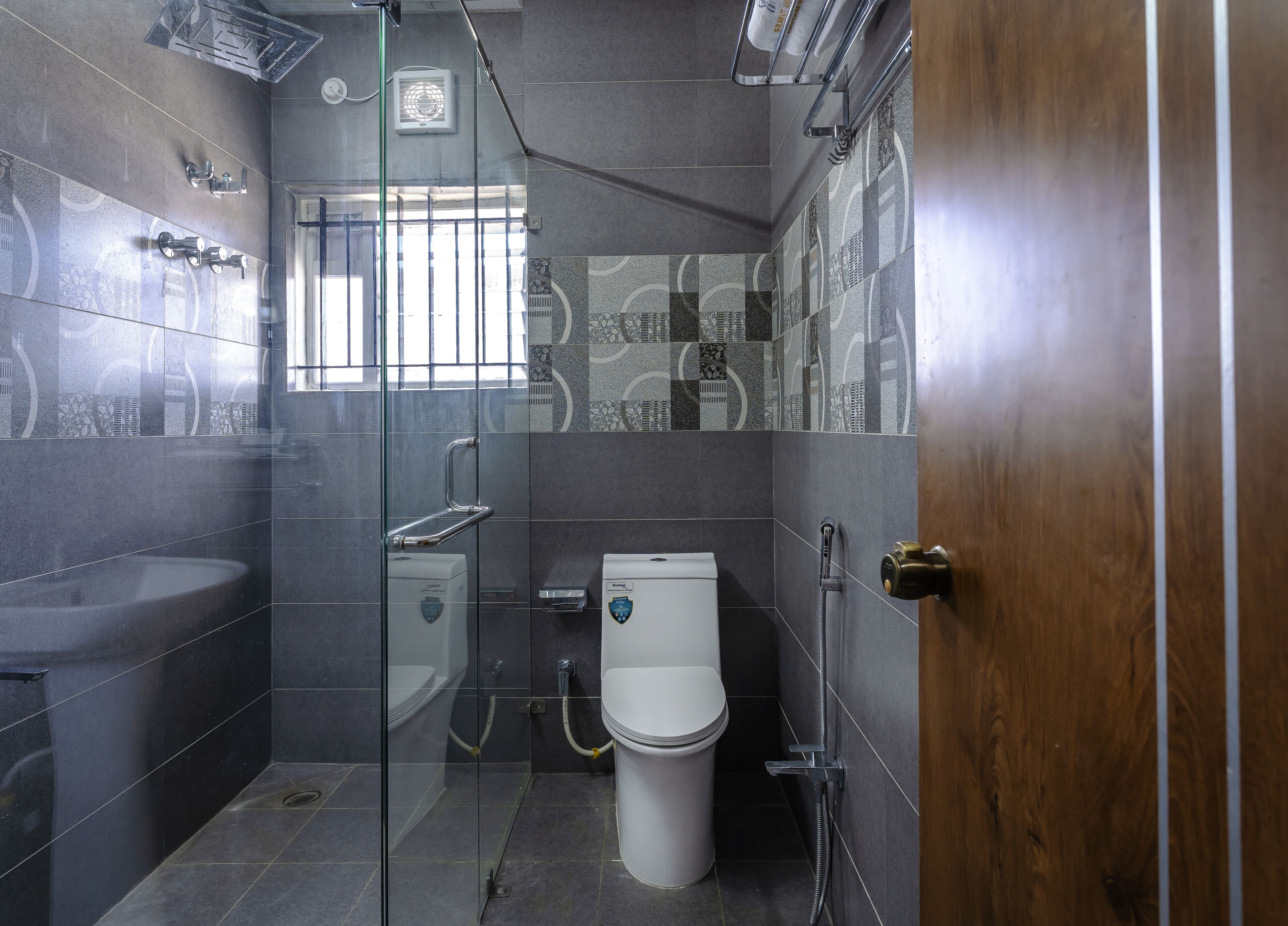A modern bathroom with a glass-enclosed shower, a white toilet, and a sink.