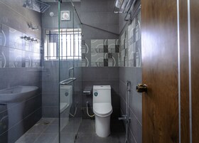 A modern bathroom with a glass-enclosed shower, a white toilet, and a sink.