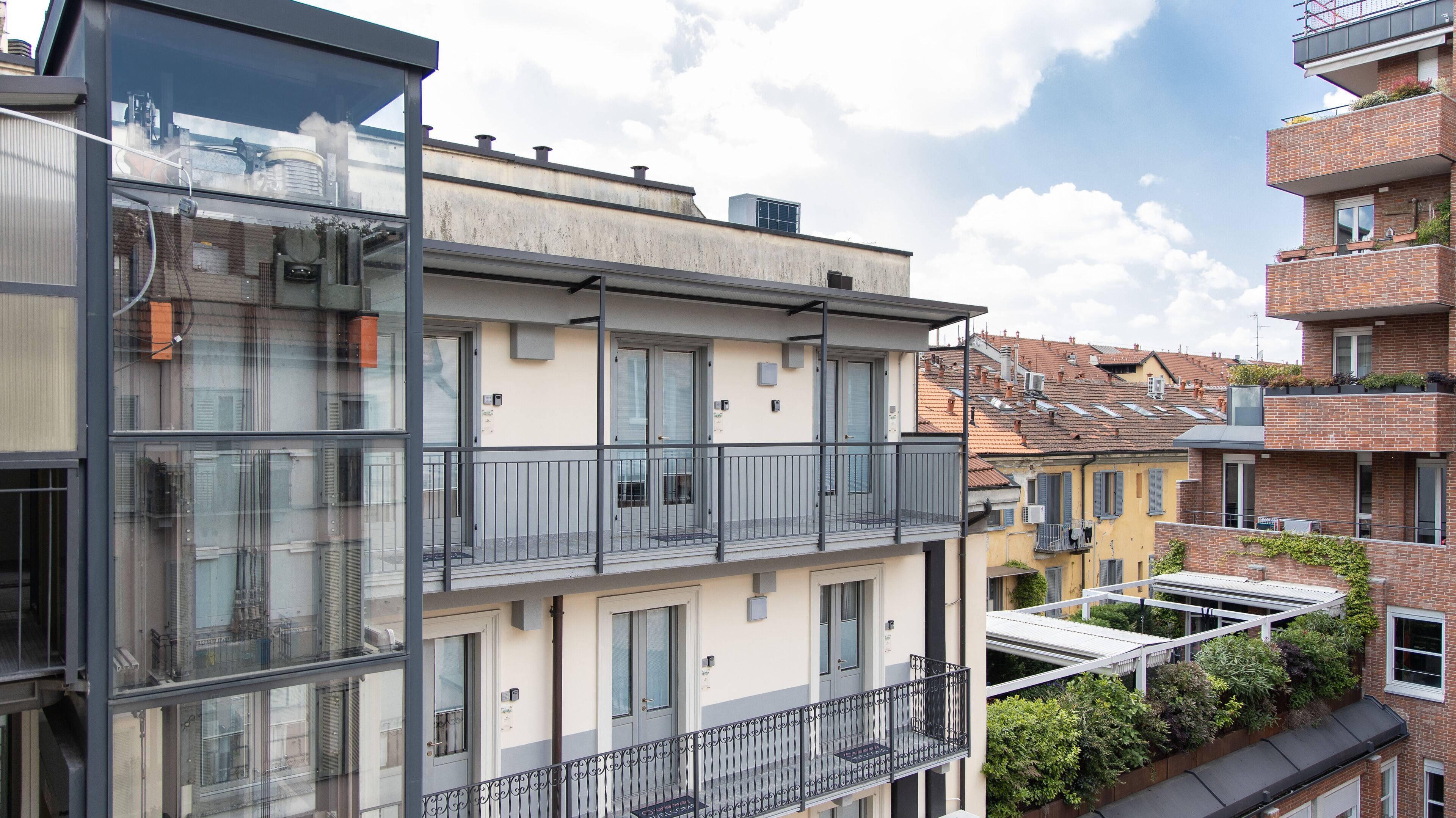 A multi-story residential building with balconies, large windows, and a mix of brick and plaster exteriors.