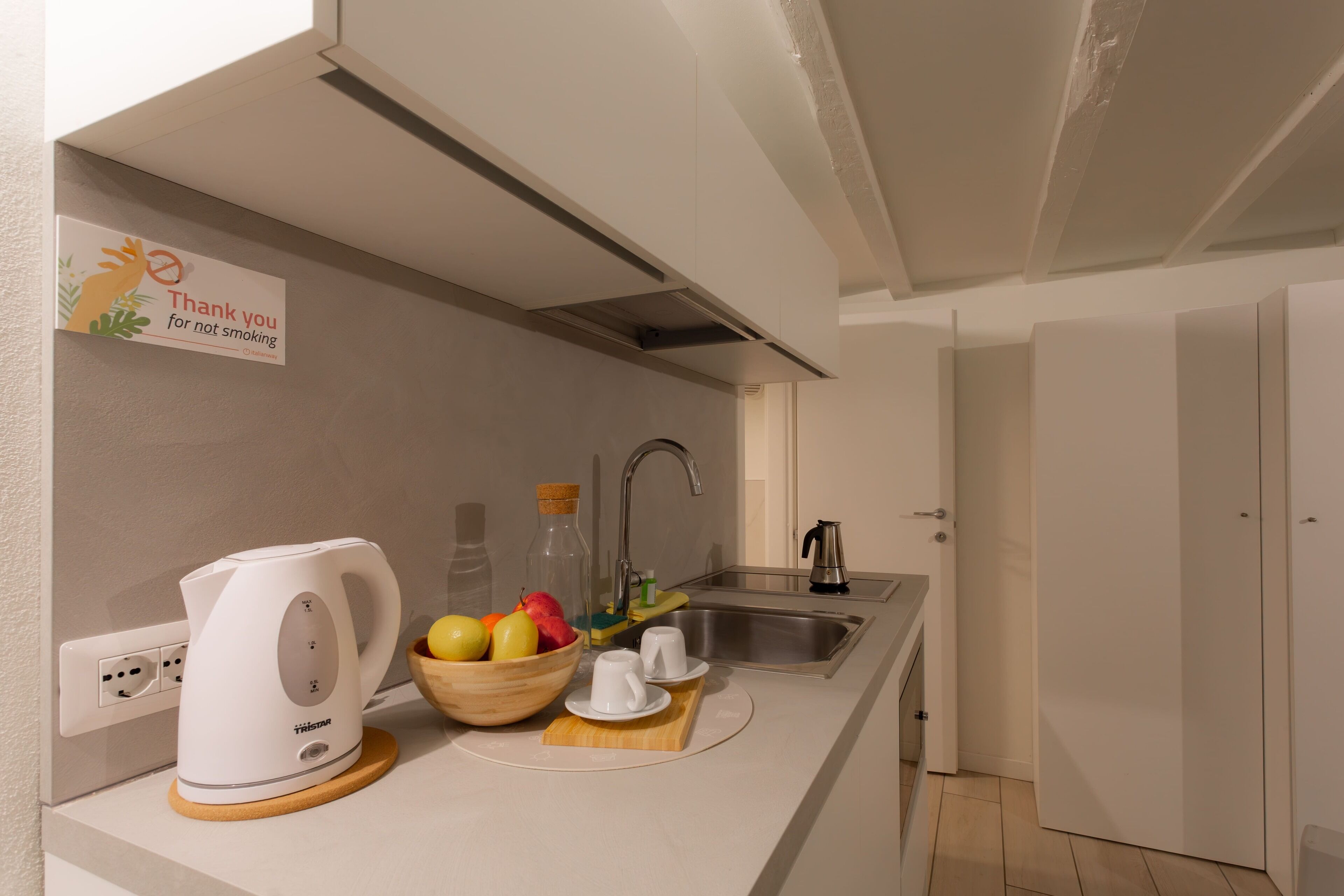 Una cocina moderna con tetera, frutero y juego de té sobre la encimera.