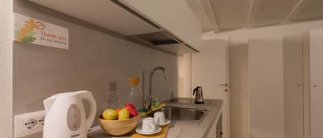 A modern kitchen with a kettle, fruit bowl, and tea set on the counter.