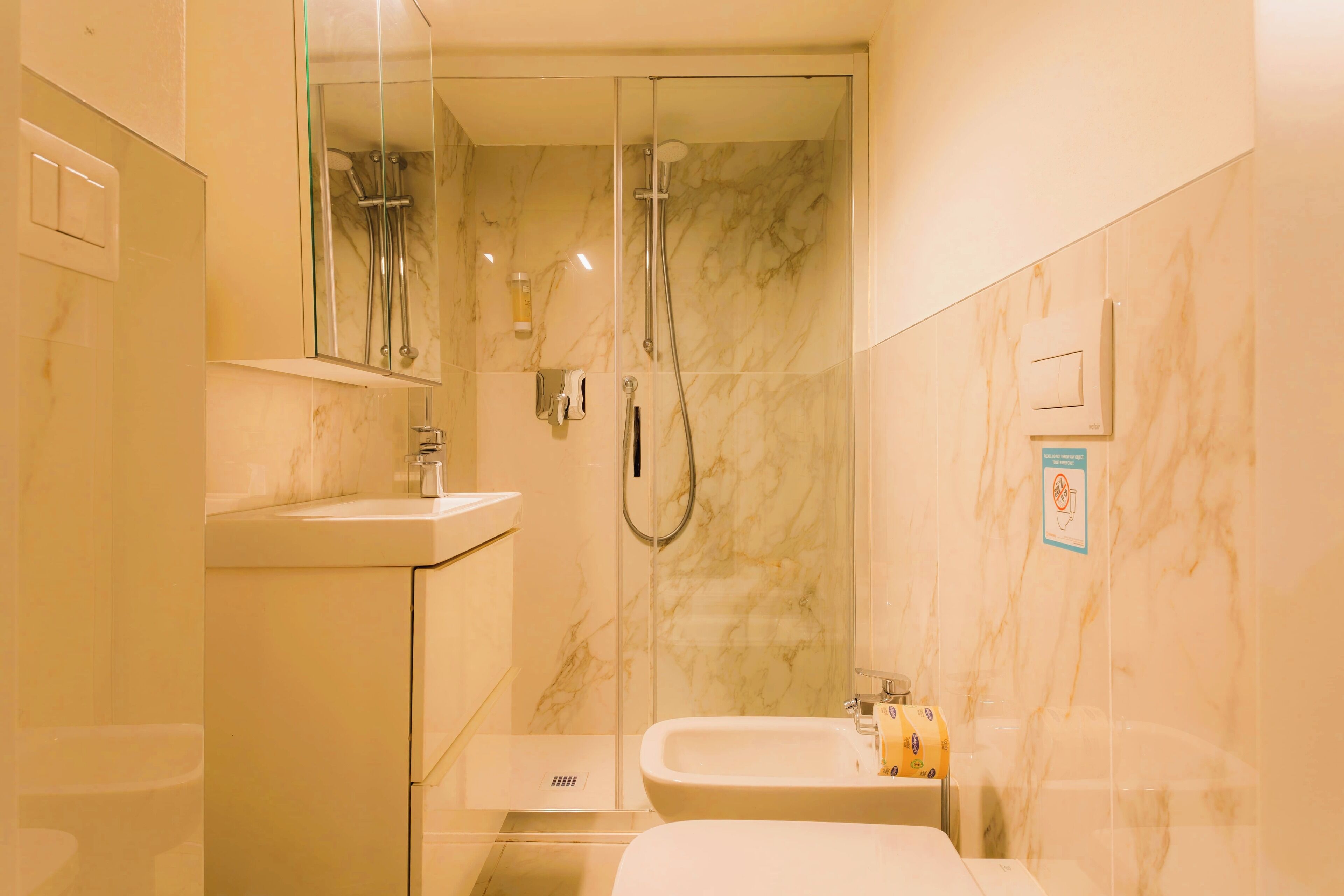 A modern bathroom with a glass-enclosed shower, a sink, and a toilet.