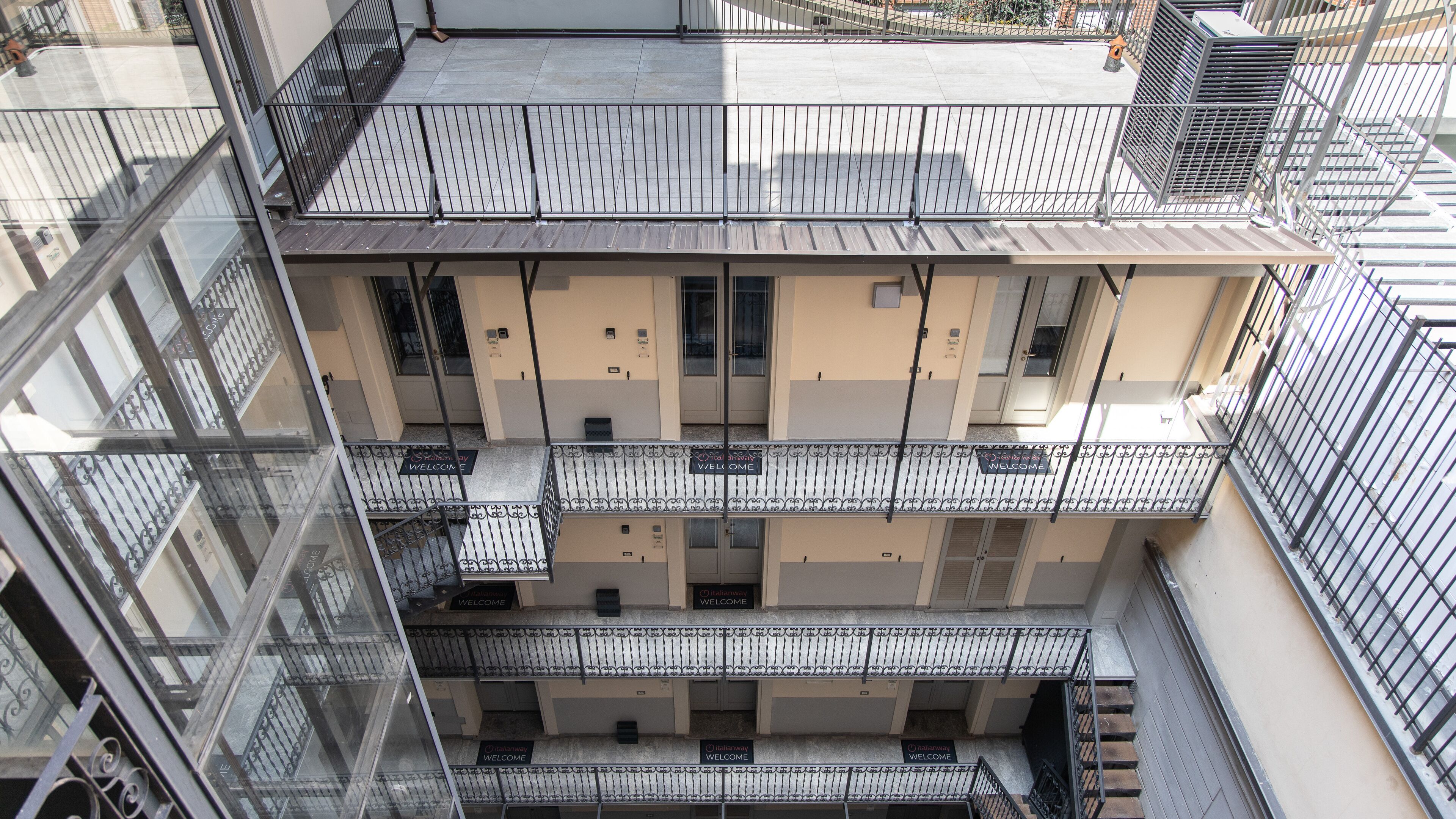 A multi-story building with balconies, a glass facade, and a sign reading "Italianway Welcome".