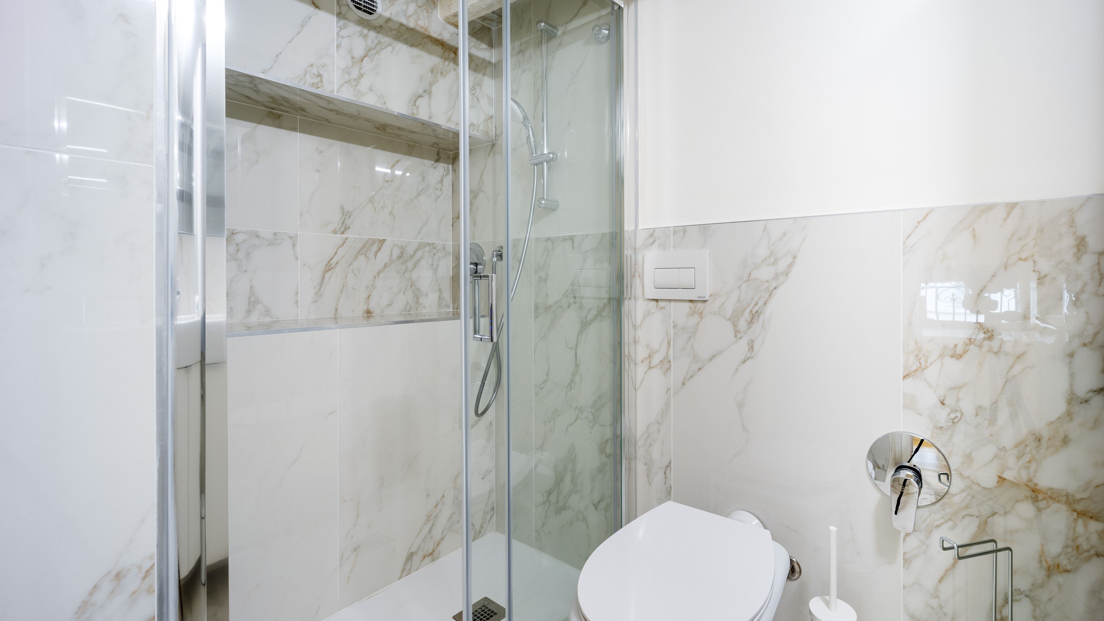 Un baño moderno con ducha vidriada, inodoro y lavamanos.