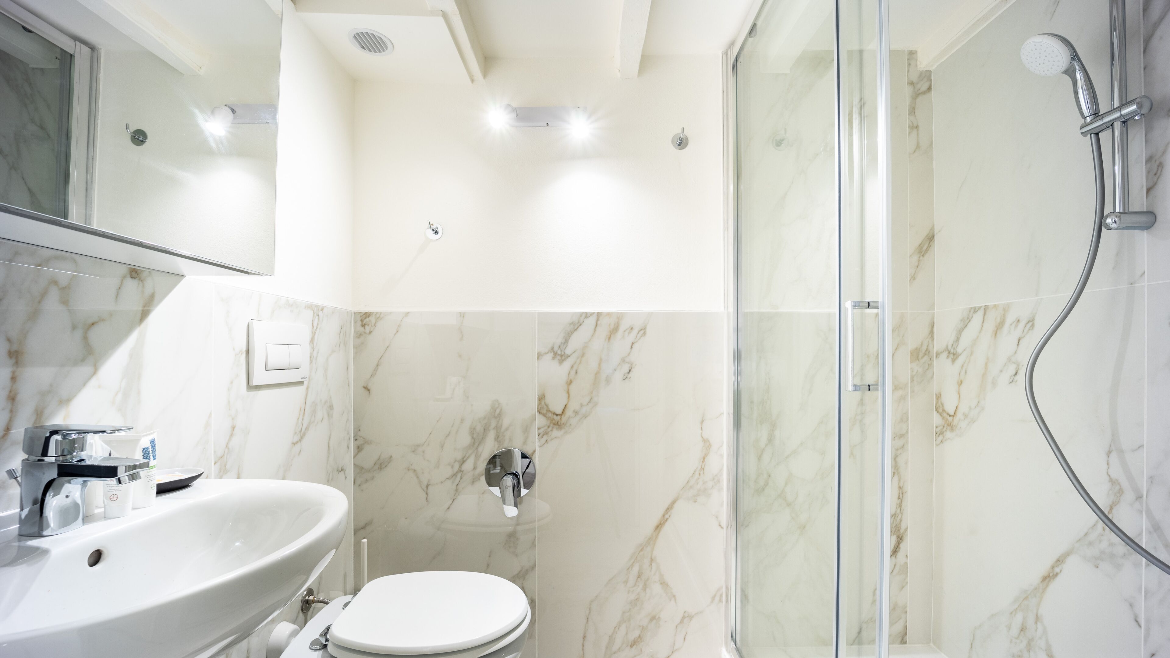 Ein modernes Badezimmer mit einer Duschkabine aus Glas, einem weißen Waschbecken und einer Toilette.
