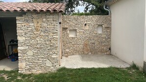 Un edificio de piedra con techo de tejas, una puerta de garaje y un ventanal pequeño.