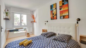 Une chambre à coucher avec un lit, un bureau et deux tableaux accrochés au mur.