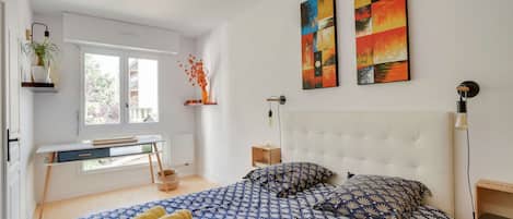 Ein Schlafzimmer mit einem Bett, einem Schreibtisch und zwei Bildern an der Wand.