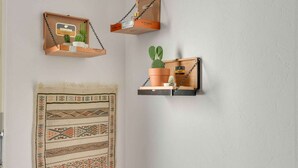 Trois étagères murales ornées de plantes et d’objets décoratifs.