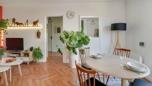 Un salon moderne avec un coin repas, un parquet en bois et diverses plantes.