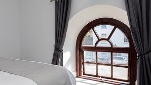A bedroom with a large arched window, a bed, and curtains. - Cozy Cove Chapel (Portland)