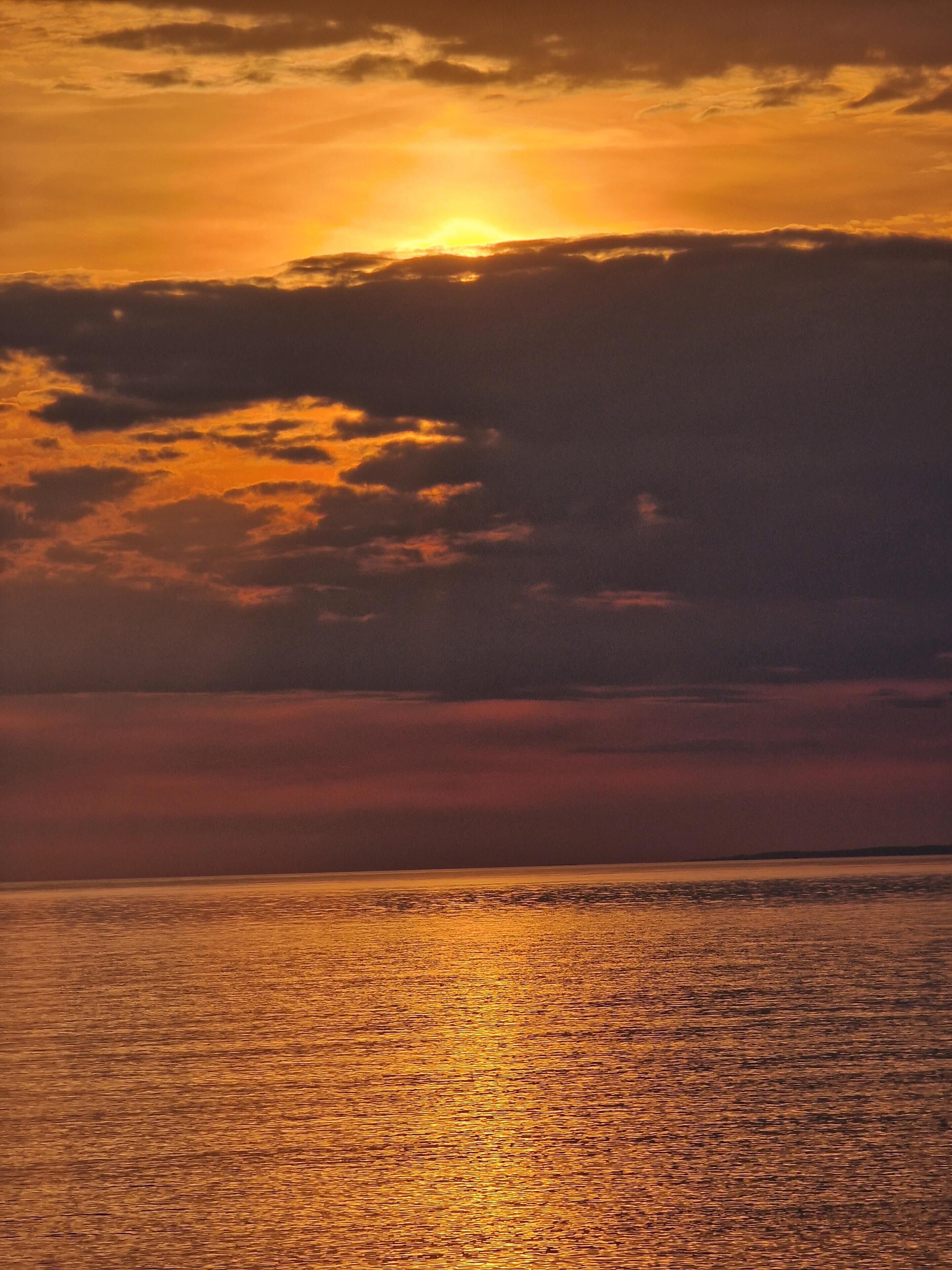 A sunset over a calm body of water with a clear horizon line.