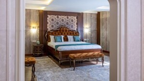 Een slaapkamer met een groot bed, een nachtkastje en een bankje.
