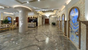 Een ruime lobby met marmeren vloeren, een receptiebalie en decoratieve wandornamenten.