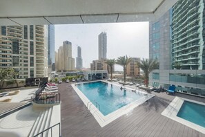 A rooftop pool with lounge chairs and a view of surrounding high-rise buildings.